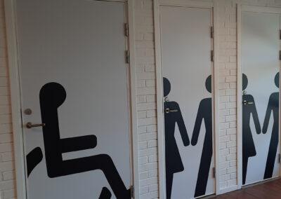 Hänvisningsskylt på WC-dörr