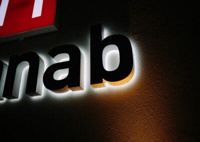 Profilbokstäver som lyser mot putsad fasad