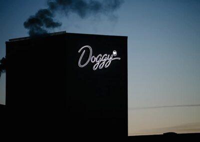 Doggy – flexled-skylt som lyser på mörk fasad mot kvällshimmel